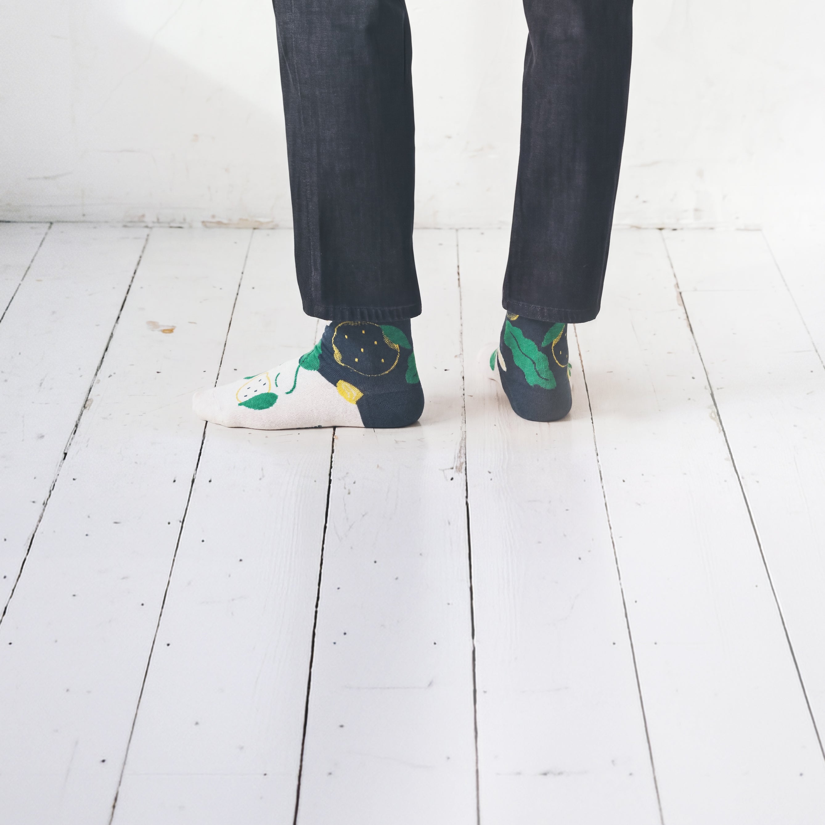 Cropped legs back view in dark jeans on white floor wearing Limono Lemonheads Black socks