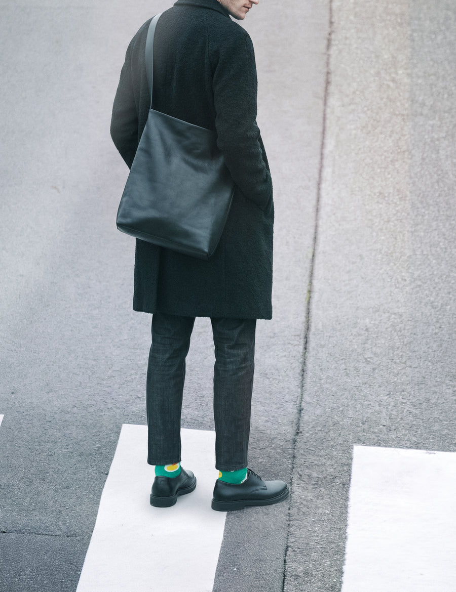 Man back view in long dark coat with leather bag at crosswalk wearing Limono Lemonheads Green socks