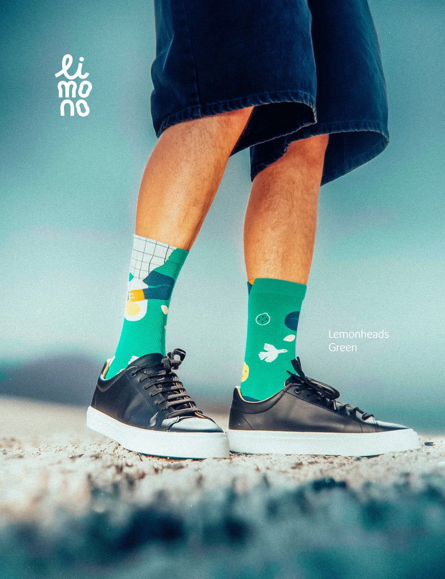 Cropped legs on stone with black sneakers wearing Limono Lemonheads Green socks