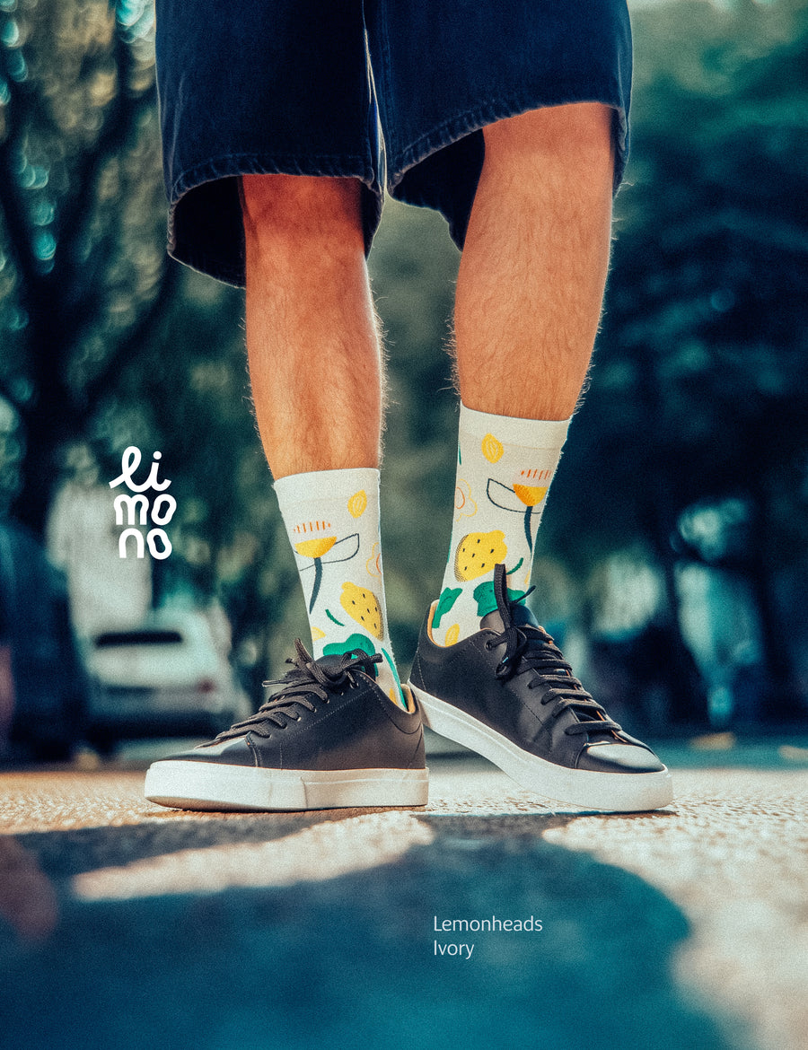 Cropped legs in street with dark sneakers wearing Limono Lemonheads Ivory socks