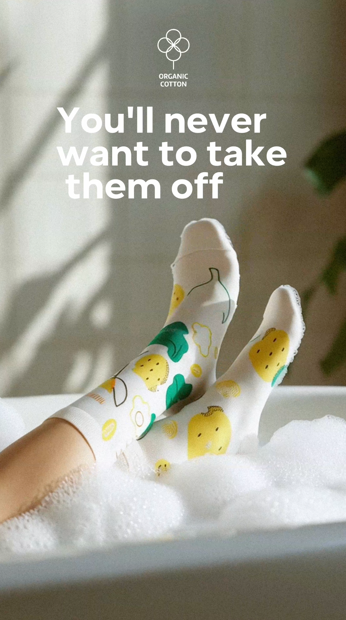 Limono Socks Lemonheads collection. Illustrated socks on trend made in Portugal. Organic combed cotton. Person wearing colorful Limono Lemonheads socks with a plant and text overlay on a light background laying in the bath foam.