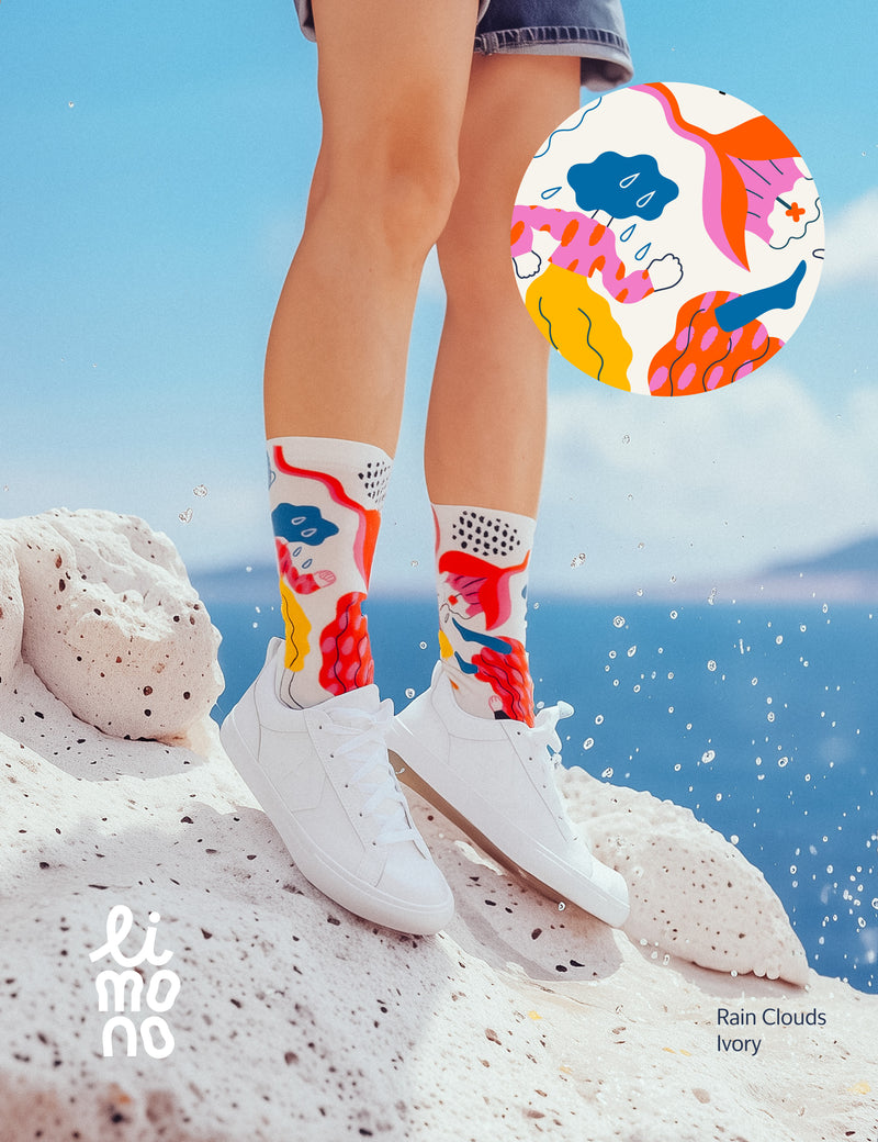 Limono Socks Rain Clouds collection. Illustrated socks on trend made in Portugal. Organic combed cotton. Person wearing colorful socks with abstract design on a rocky surface.