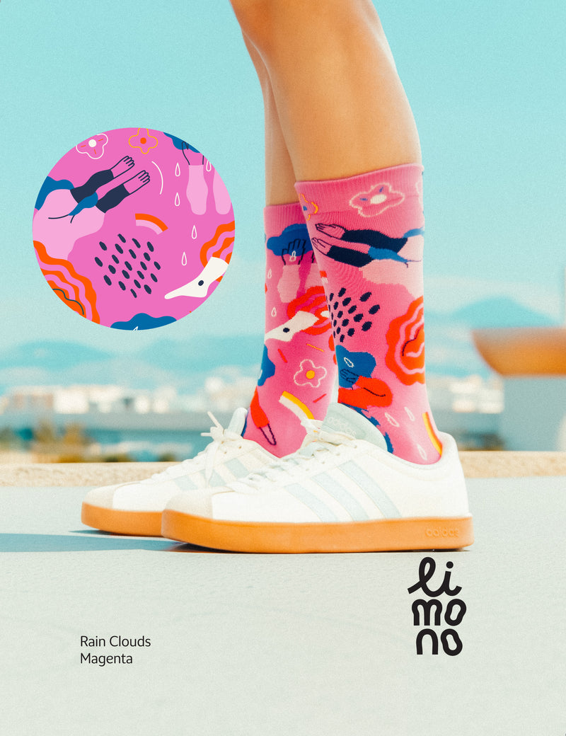 Limono Socks Rain Clouds collection. Illustrated socks on trend made in Portugal. Organic combed cotton. Colorful socks with a 'Rain Clouds Magenta' design on a blurred outdoor background, featuring the brand 'limono'.