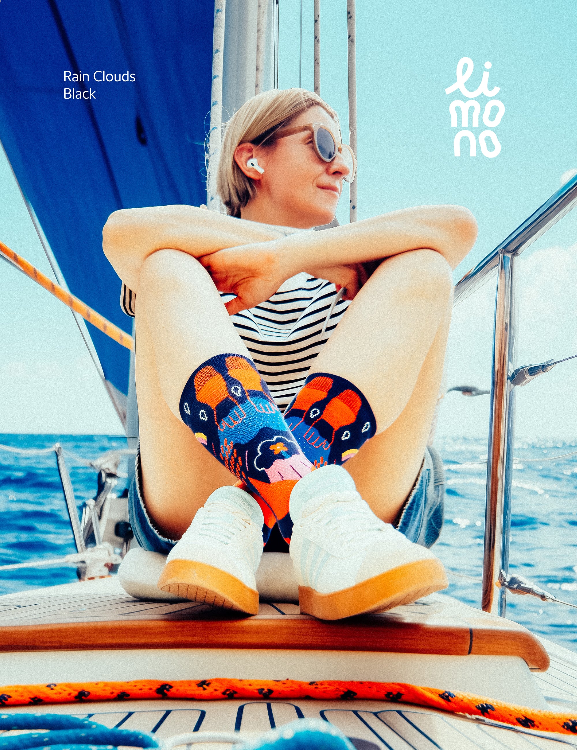 Limono Socks Rain Clouds collection. Illustrated socks on trend made in Portugal. Organic combed cotton. Person sitting on a sailboat wearing colorful socks with a brand logo in the corner.