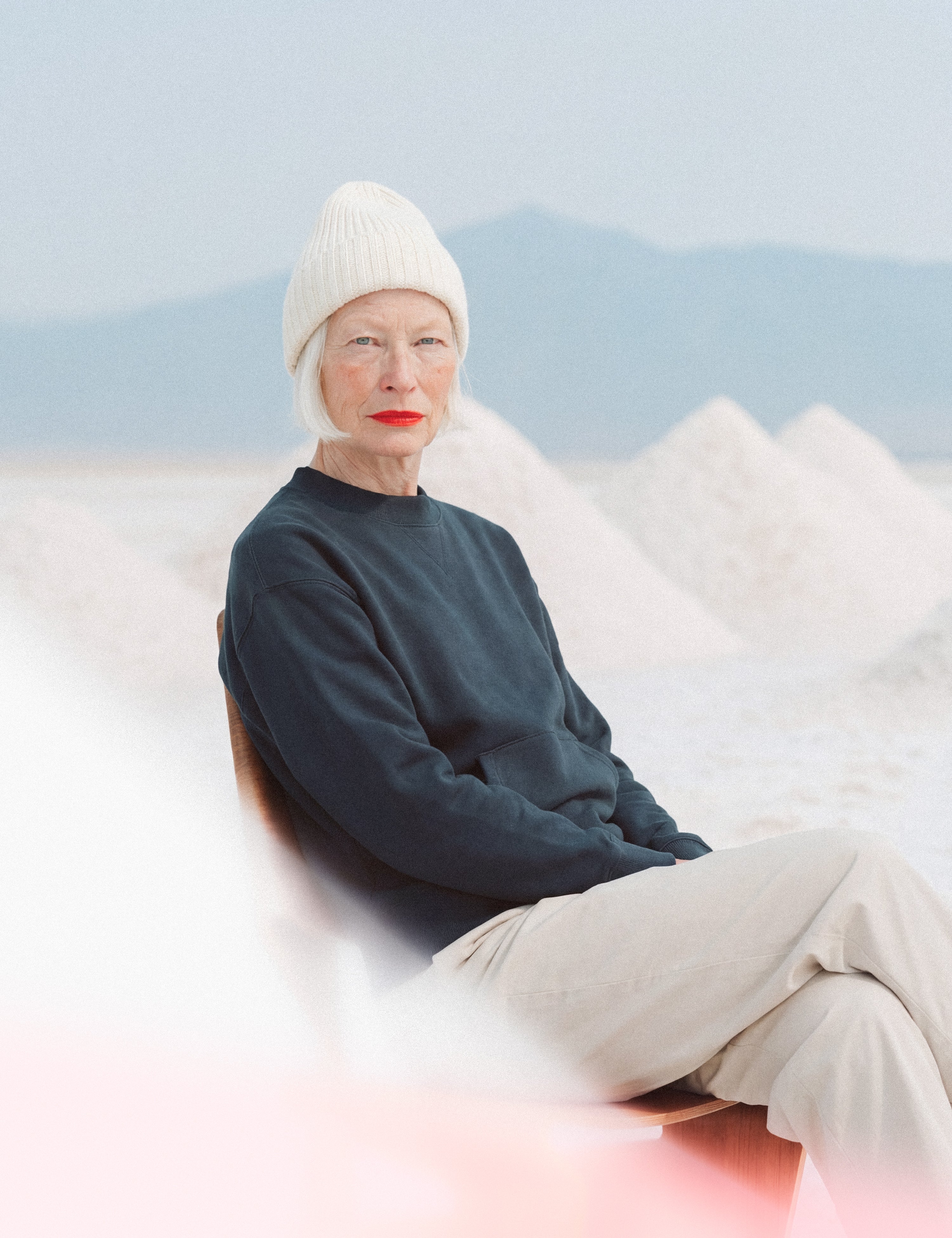 Limono Robots Day Red campaign portrait, model in beanie seated against salt mounds in desert