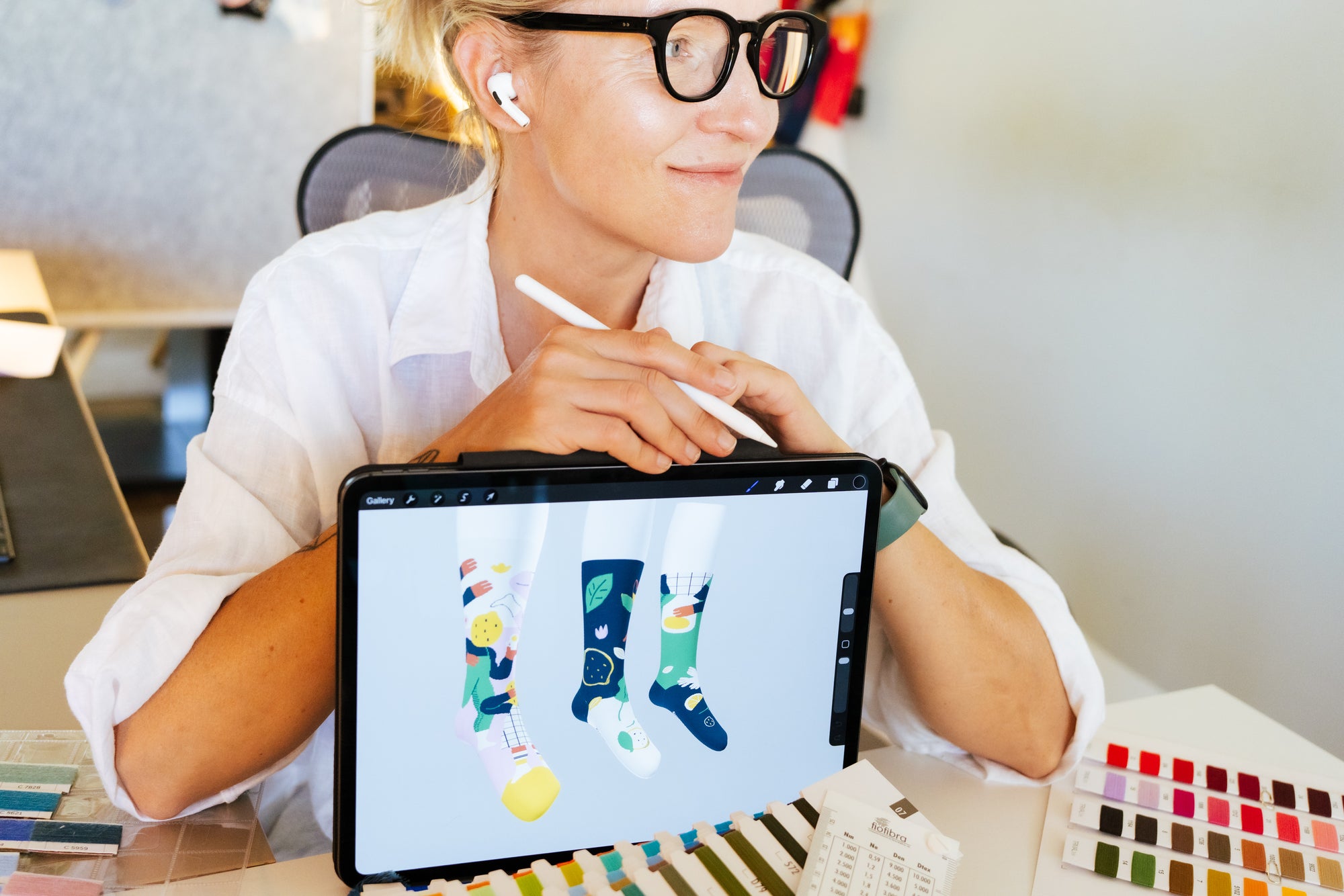 Illustrator Oksana Grivina at her studio desk drawing Limono sock designs on iPad