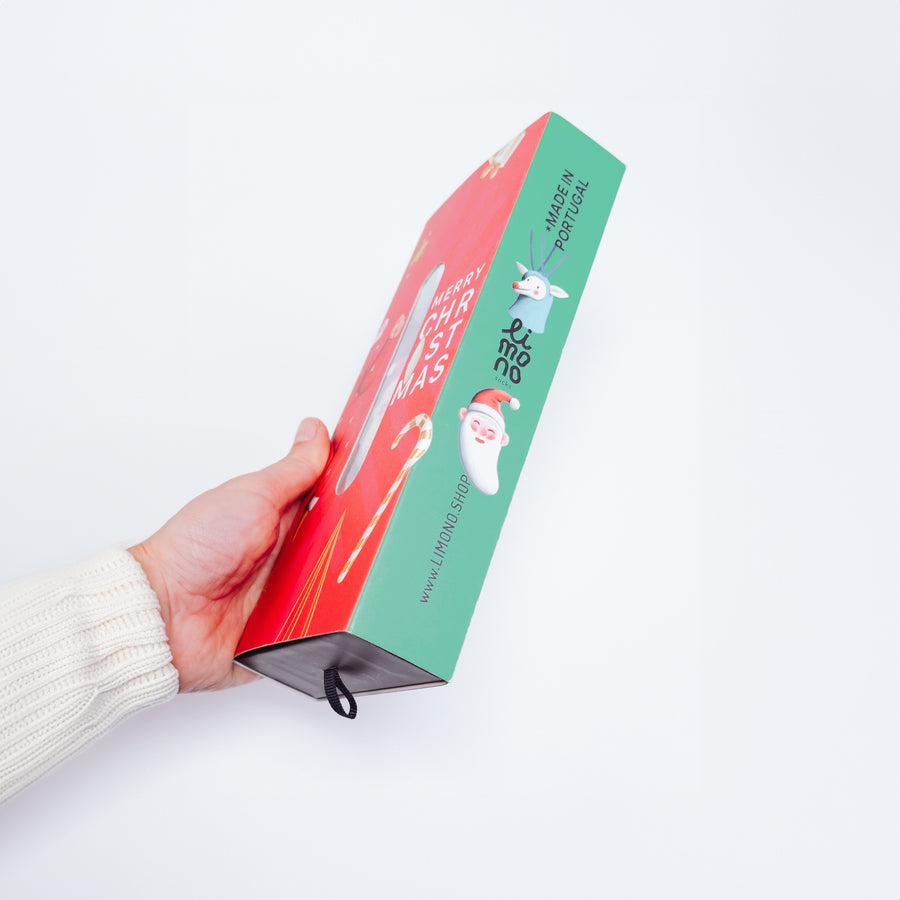 Hand in cream sweater holding the Limono Christmas gift box side view, Made in Portugal