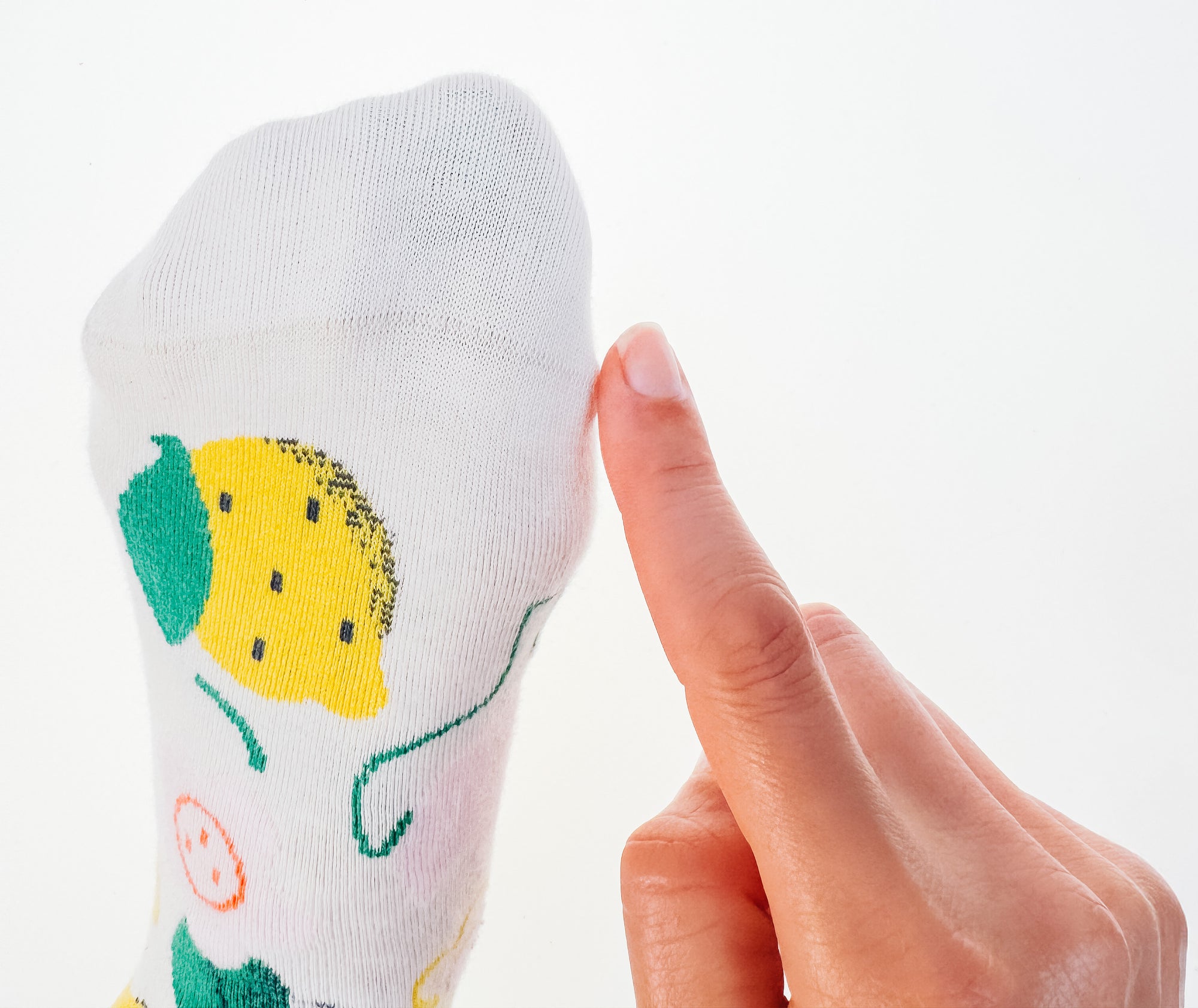 Finger touching the seamless toe of a Limono Lemonheads Ivory sock close-up