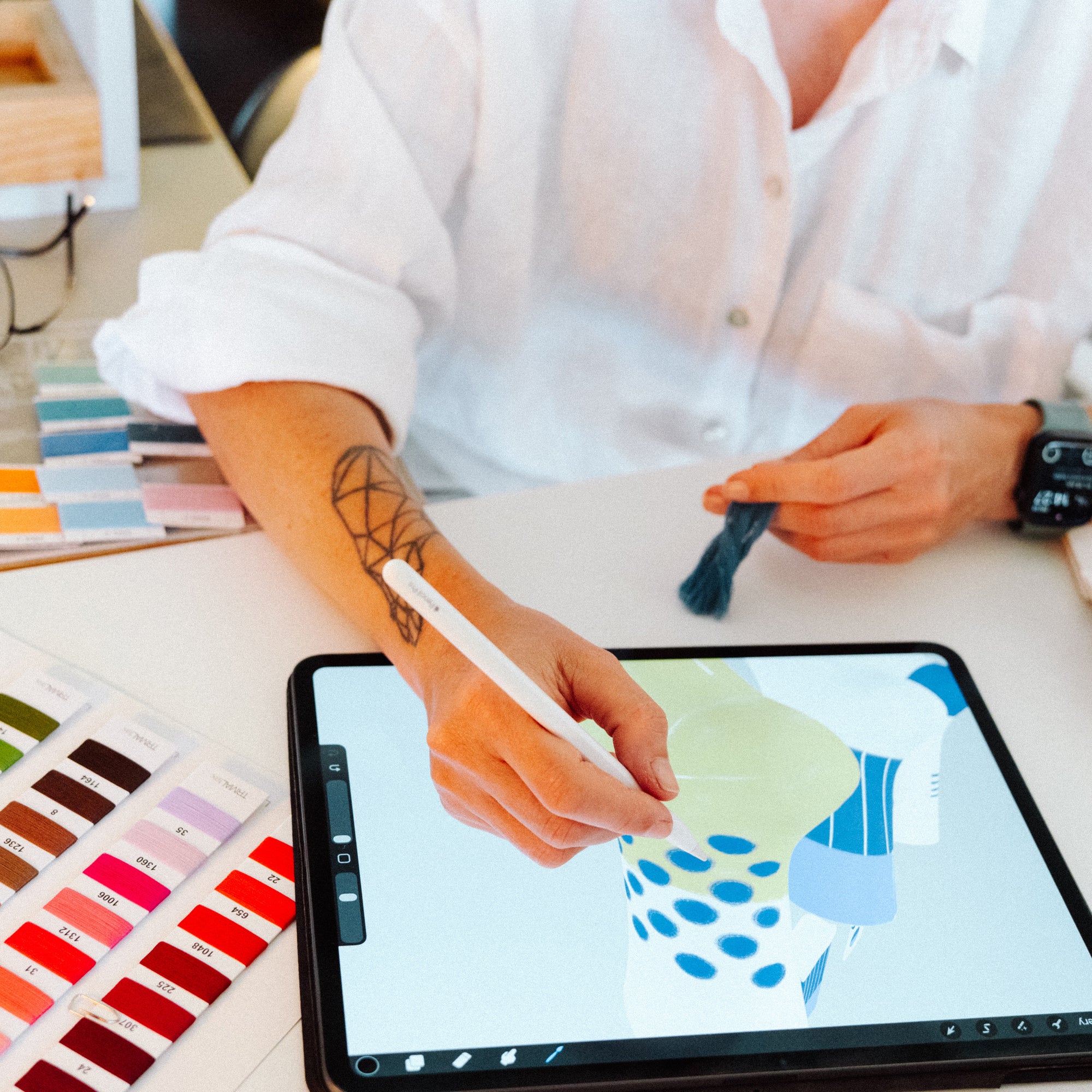 Studio shot of designer drawing a Limono sock on iPad with color thread swatches on the table