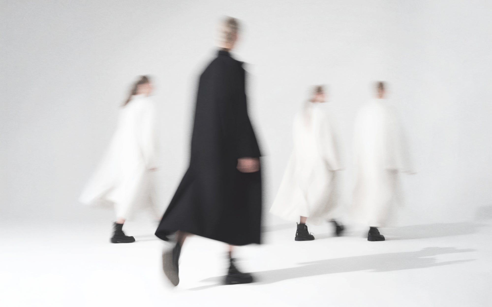 Limono editorial of figures in long white coats and one black coat walking, soft focus