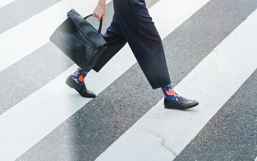 Limono Rain Clouds Black socks worn with navy pants on a zebra crosswalk, horizontal crop