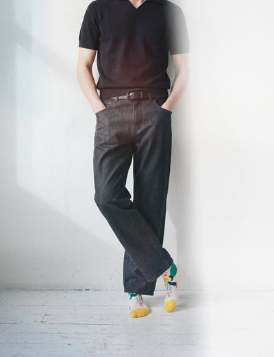 Man in dark v-neck and brown jeans leaning on white wall wearing Limono Lemonheads Rose socks