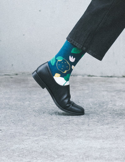 Cropped foot profile in dark trousers and leather boot wearing Limono Lemonheads Black sock