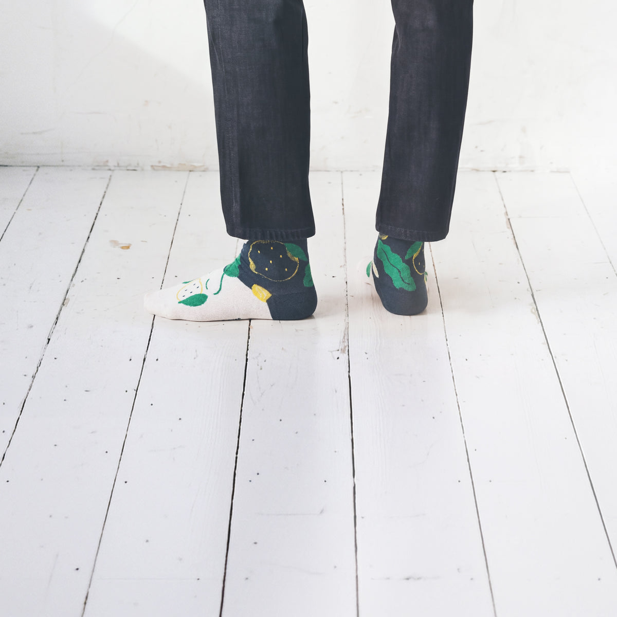 Cropped legs back view in dark jeans on white floor wearing Limono Lemonheads Black socks