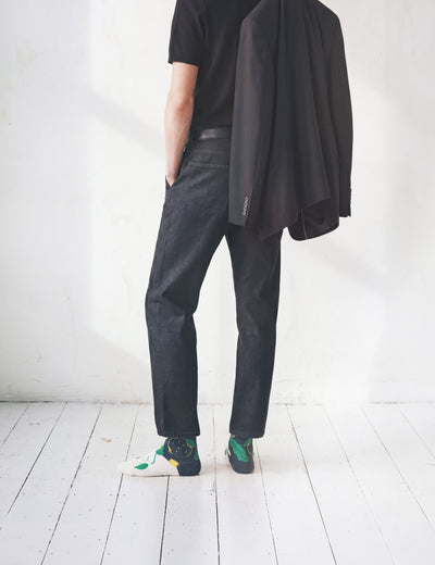 Man back view in black tee and dark denim with jacket over arm wearing Limono Lemonheads Black socks