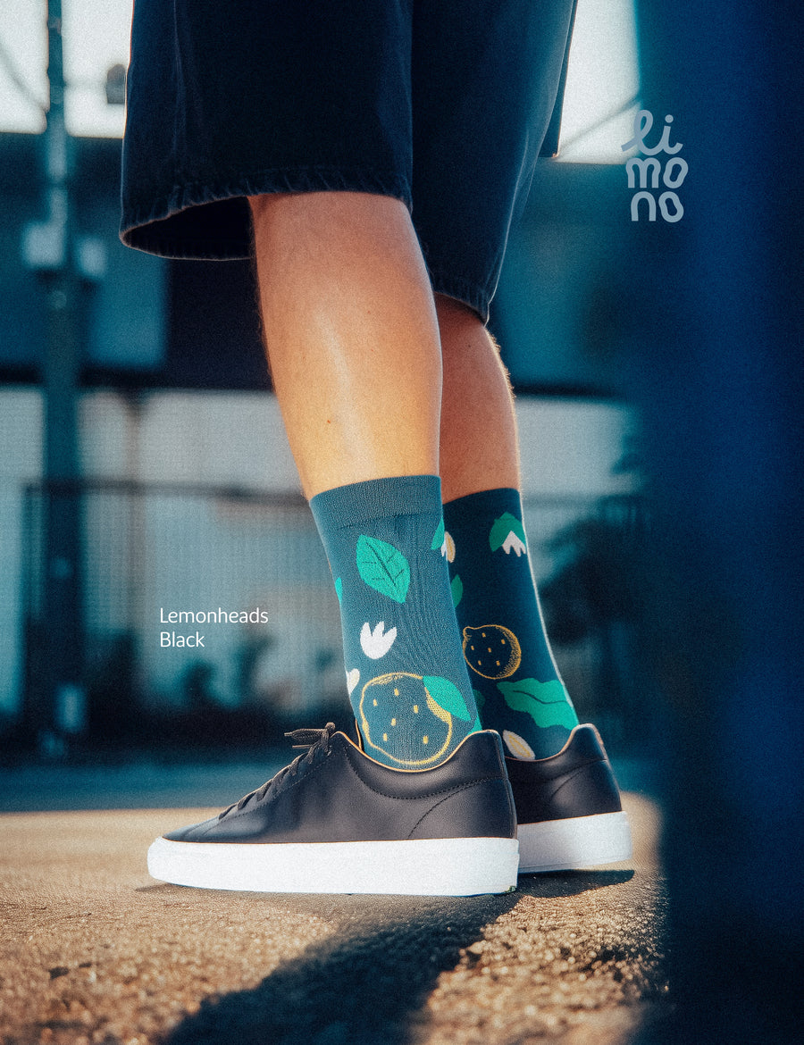 Cropped legs on industrial street with black sneakers wearing Limono Lemonheads Black socks