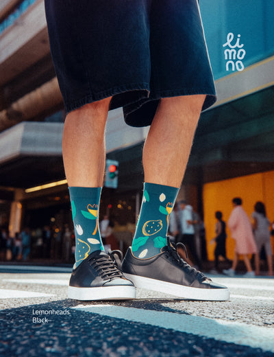 Cropped legs at crosswalk with black sneakers wearing Limono Lemonheads Black socks