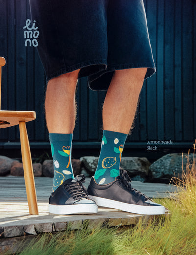 Cropped legs on wooden porch with black sneakers wearing Limono Lemonheads Black socks