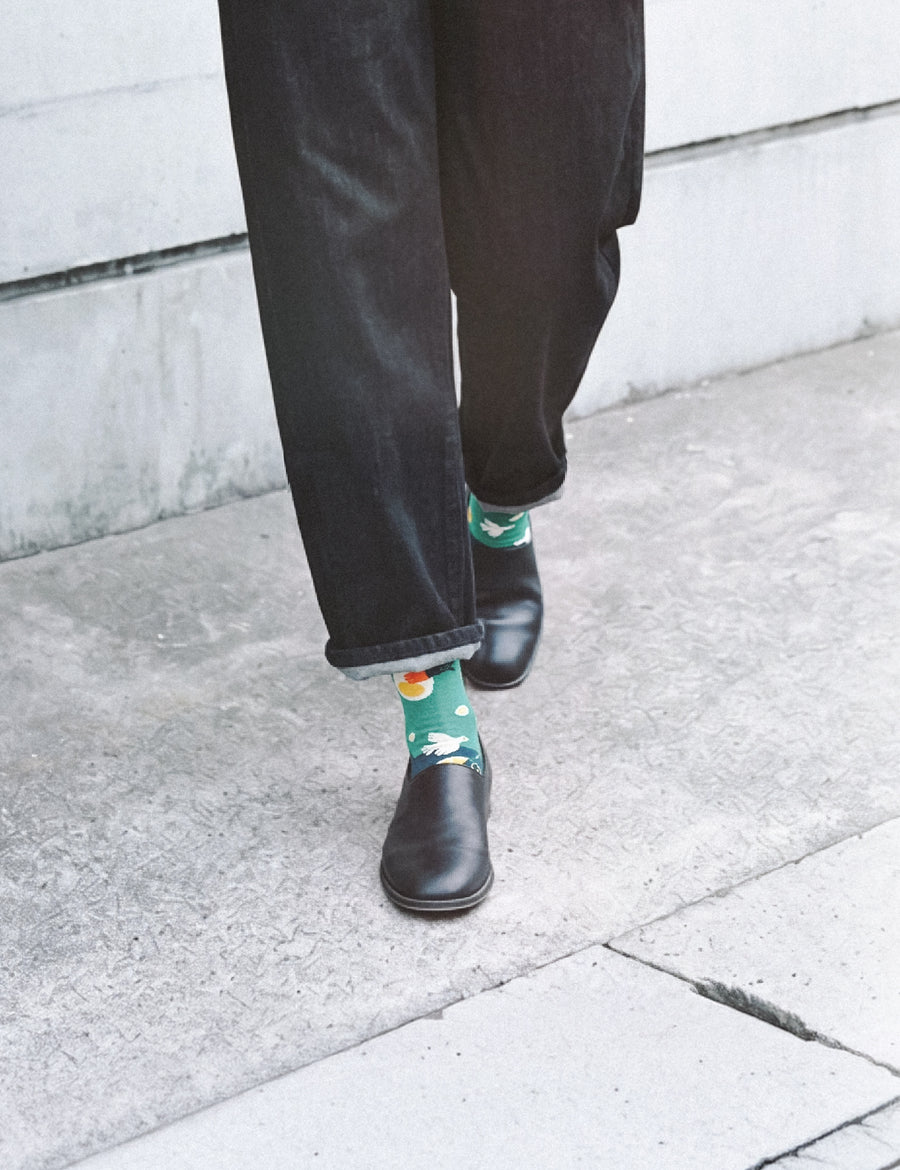 Cropped walk on sidewalk in dark jeans and leather boots with Limono Lemonheads Green socks peeking
