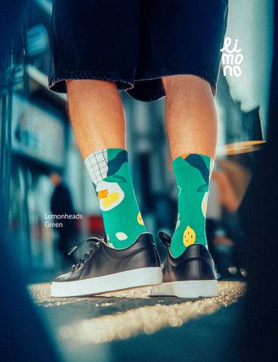 Cropped legs walking in the city with dark sneakers wearing Limono Lemonheads Green socks