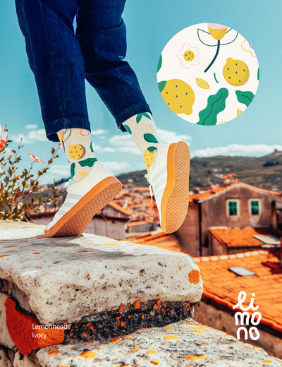Limono Lemonheads Ivory socks with lemons and flowers, worn with sneakers above terracotta rooftops