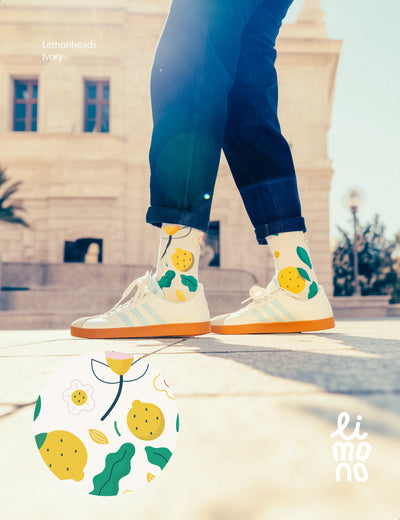 Limono Lemonheads Ivory socks with lemons and flowers, worn with sneakers on a sunlit stone plaza