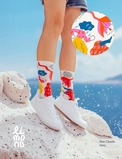 Limono Socks Rain Clouds collection. Illustrated socks on trend made in Portugal. Organic combed cotton.  Person wearing colorful socks with abstract design on a rocky surface.