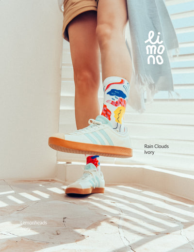 Cropped legs on stairs with white sneakers wearing Limono Rain Clouds White socks