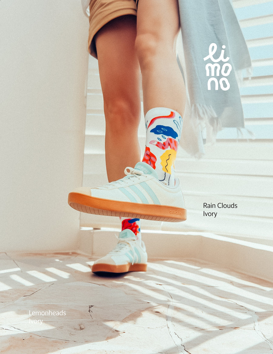 Cropped legs on stairs with white sneakers wearing Limono Rain Clouds White socks