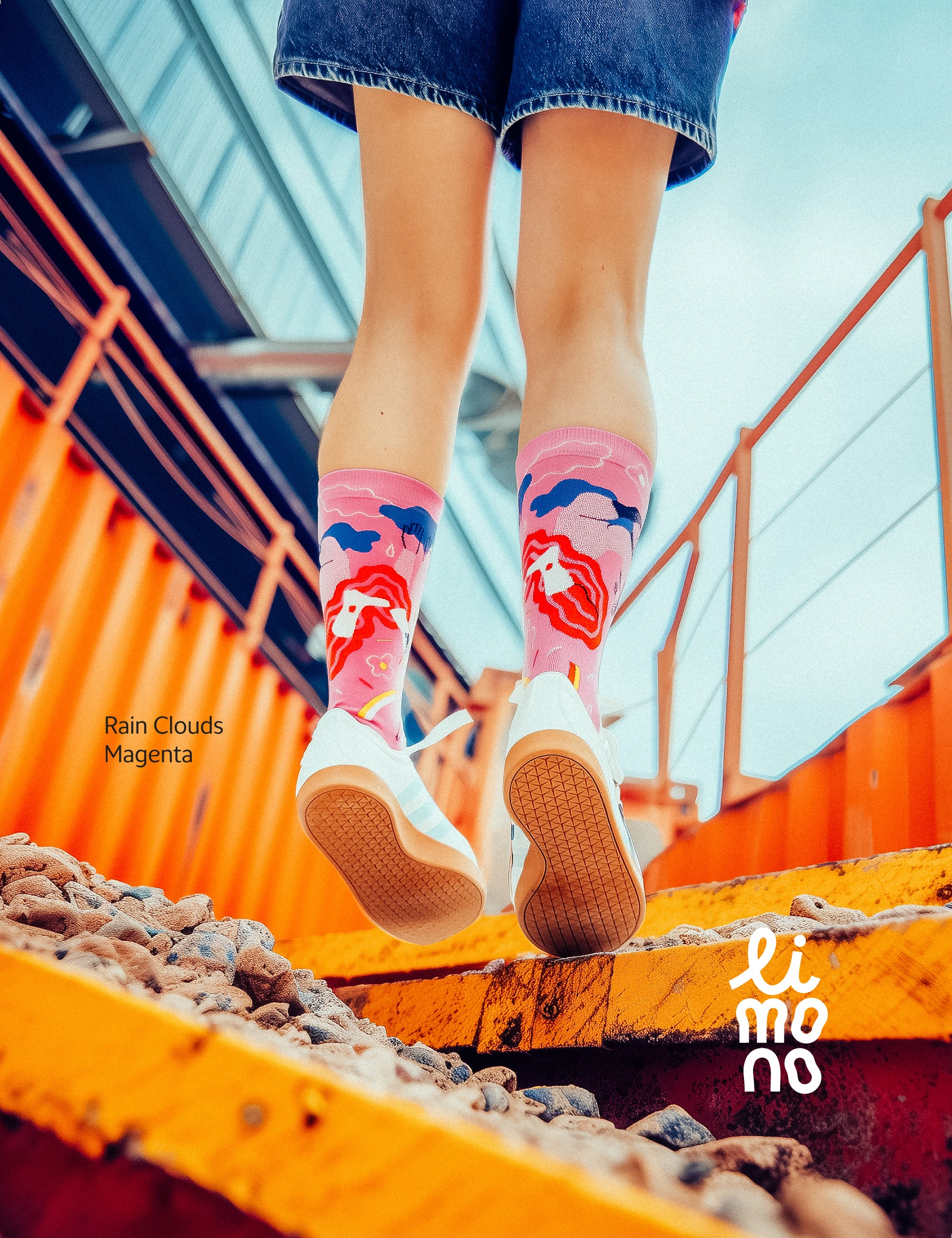 Limono Socks Rain Clouds collection. Illustrated socks on trend made in Portugal. Organic combed cotton. Person wearing colorful socks with cloud design on a bright day, with 'limono' brand visible.