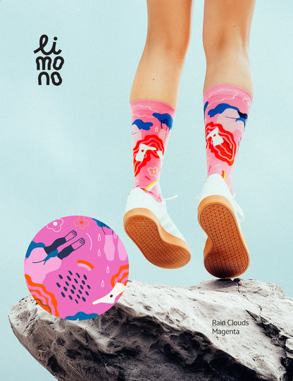 Limono Socks Rain Clouds collection. Illustrated socks on trend made in Portugal. Organic combed cotton. Person wearing colorful socks with a ball, standing on a rock against a light blue background.
