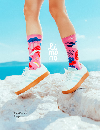 Limono Socks Rain Clouds collection. Illustrated socks on trend made in Portugal. Organic combed cotton. Person wearing colorful socks with a blue sky and white clouds in the background