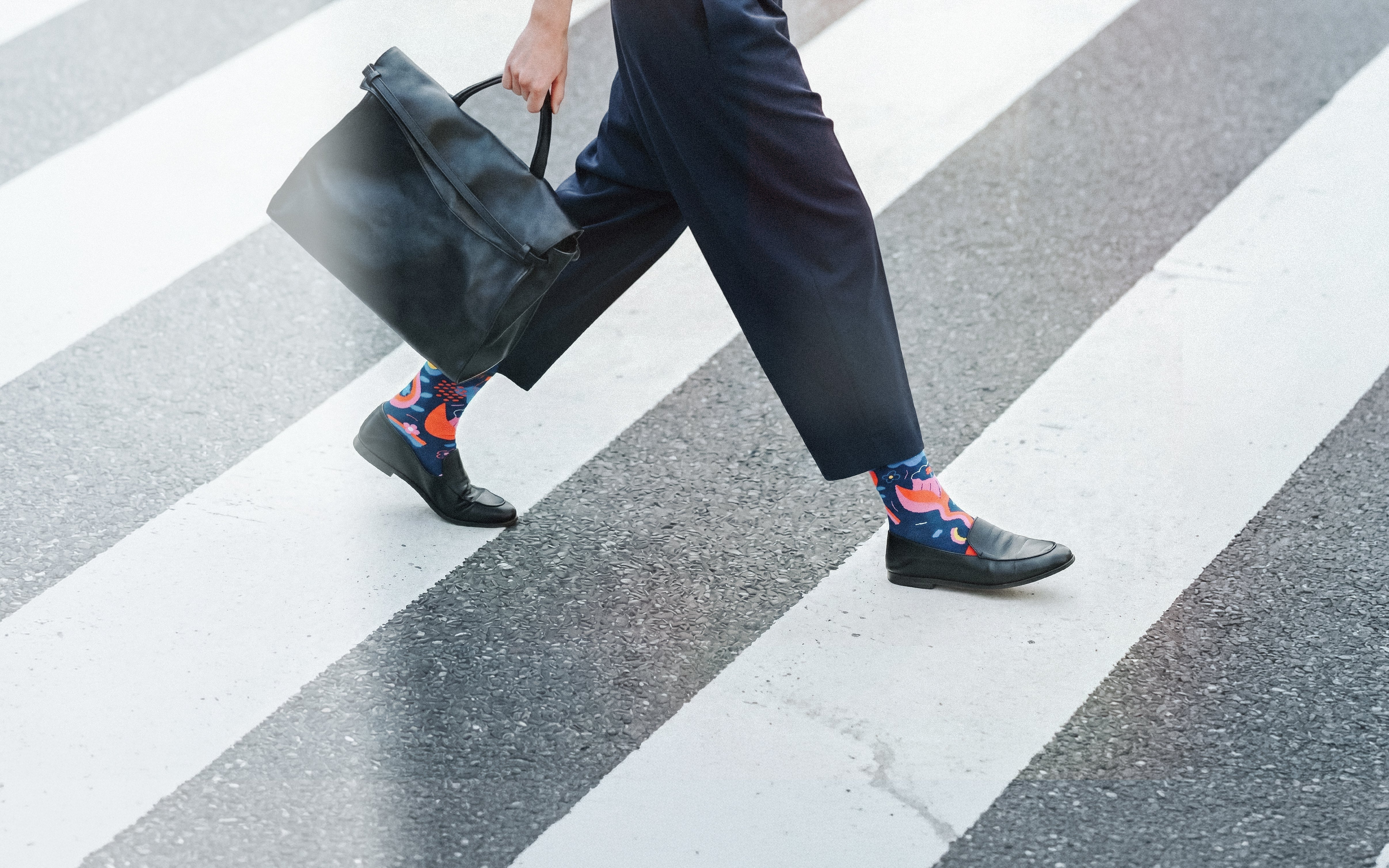 Limono Rain Clouds Black socks worn with navy pants on a zebra crosswalk, horizontal crop