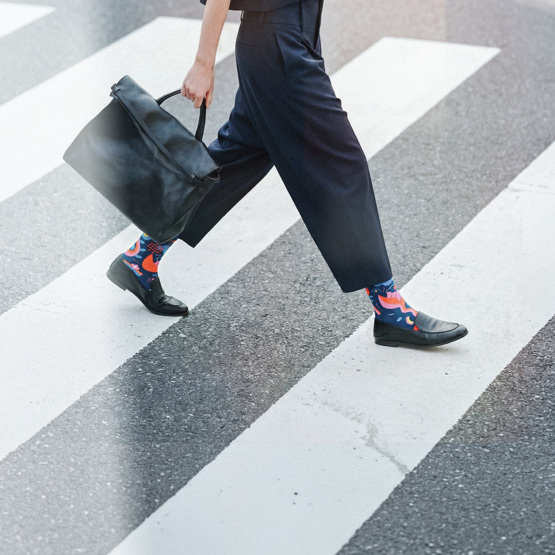 Limono Rain Clouds Black socks worn with navy pants and black loafers crossing a zebra crosswalk