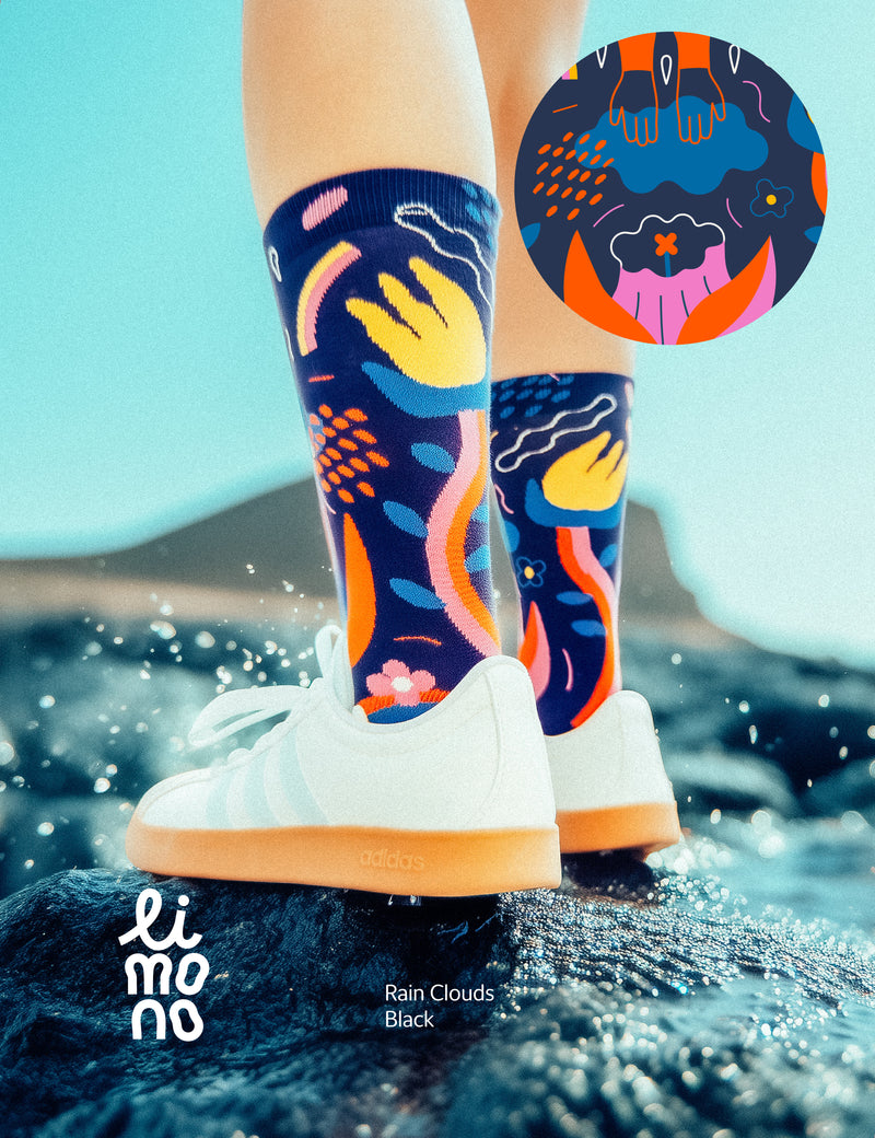 Limono Socks Rain Clouds collection. Illustrated socks on trend made in Portugal. Organic combed cotton. Colorful socks with abstract patterns worn by a person standing on water, with 'limono' branding.