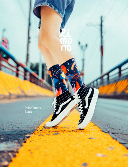 Limono Socks Rain Clouds collection. Illustrated socks on trend made in Portugal. Organic combed cotton. Person wearing colorful socks and black sneakers on a road with 'moncler' branding.