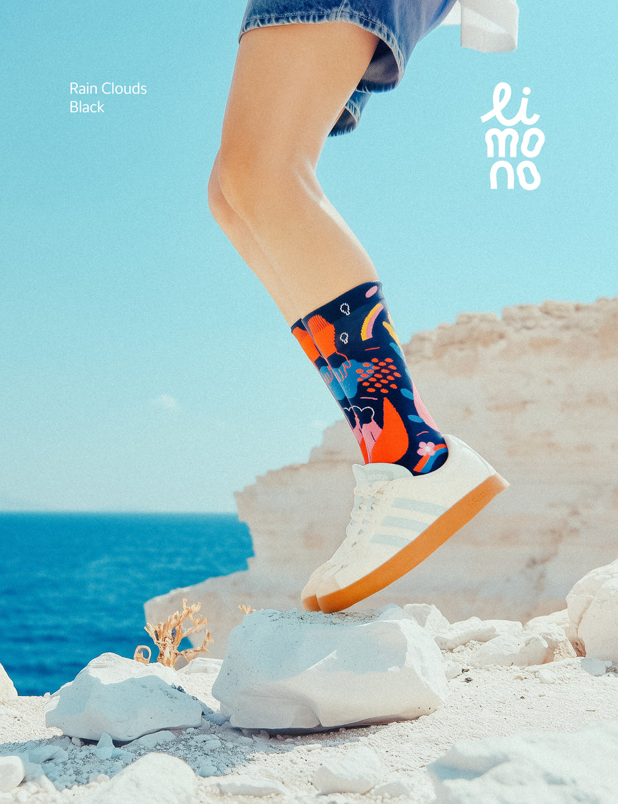 Limono Rain Clouds Black socks with white Adidas sneakers on white limestone rock by the sea
