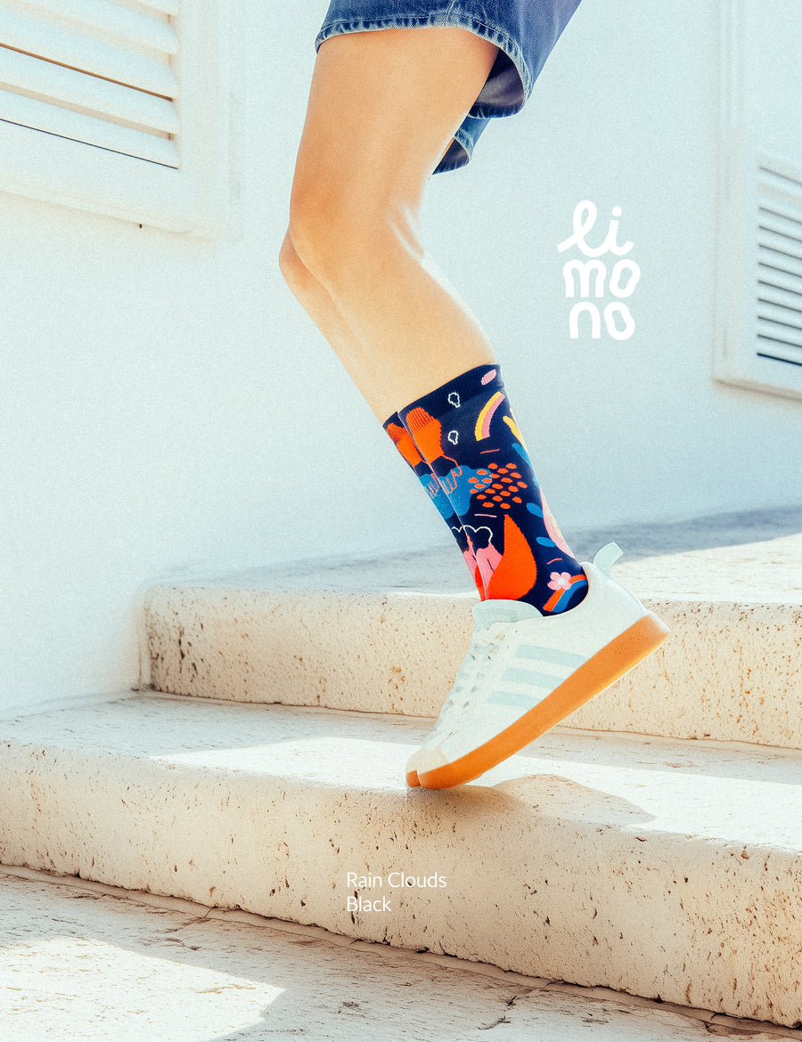 Lifestyle jump shot on a stone step, wearing Limono Rain Clouds Black socks with white sneakers