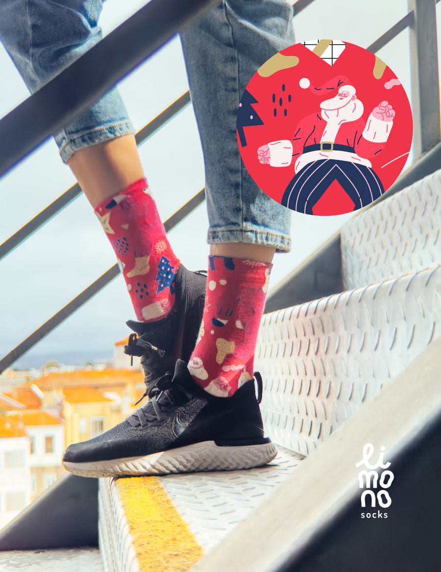 Limono Christmas Red socks worn with black sneakers on metal stairs, Santa illustration overlay