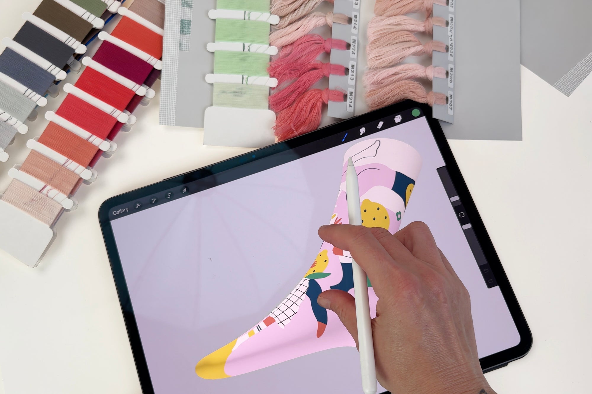 Top down studio shot of designer drawing a Limono sock on iPad with color thread swatches